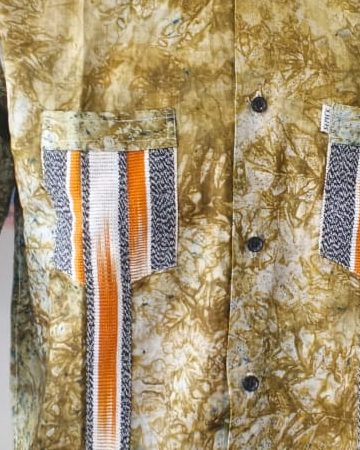 Poche en pagne tissé rayé orange sur une chemise batik kaki